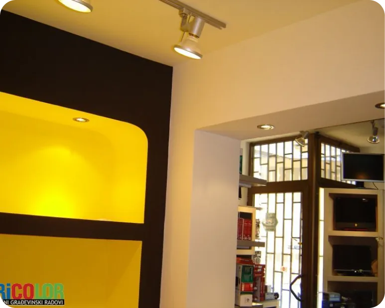 Enterijer sa dekorativnim zutim osvetljenjem i policama